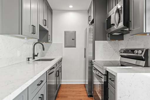 a renovated kitchen with marble counter tops and stainless steel appliances
