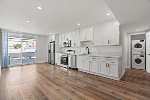 a white kitchen with a washer and dryer and white cabinets