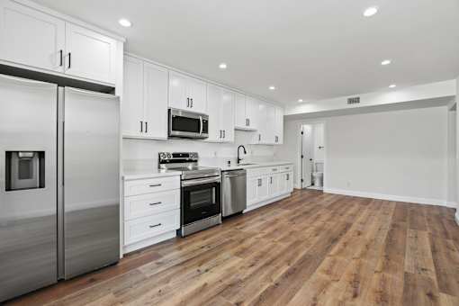 a renovated kitchen with white cabinets and stainless steel appliances