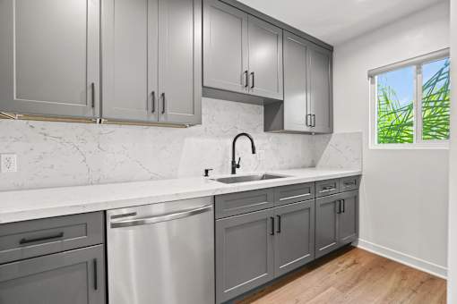 a white and gray kitchen with stainless steel appliances and a window