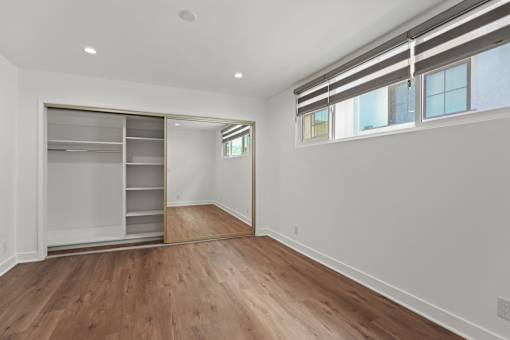 a room with white walls and wood floors and a closet with a window