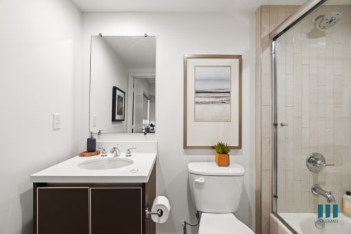 Bathroom with Full-Size Bathtub with Glass Door and Cabinet Storage