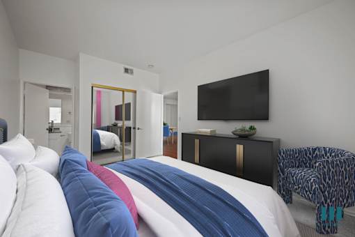 A bedroom with a bed covered in a white, blue and red comforter.