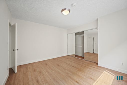 Bedroom with a Mirrored Closet and Vinyl Flooring