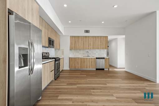 A modern kitchen with wooden cabinets and a stainless steel refrigerator.