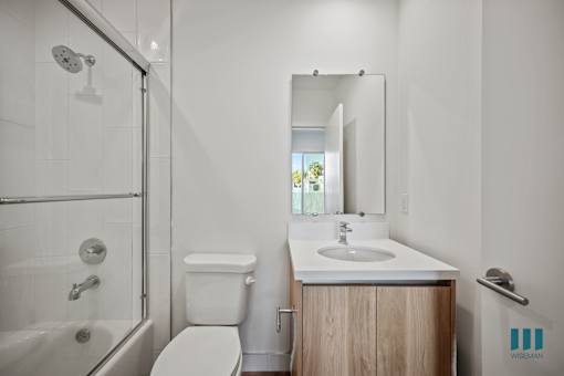 A bathroom with a white toilet, sink, and a glass shower stall.