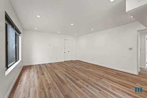 A room with wooden flooring and white walls.