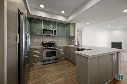 A modern kitchen with stainless steel appliances and wooden floors.