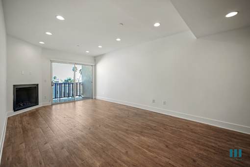 A spacious room with wooden flooring and a fireplace.