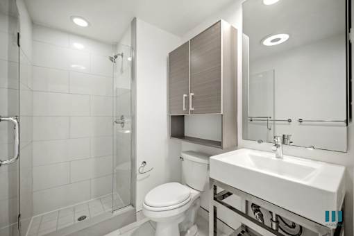 A white toilet sits next to a sink in a modern bathroom.