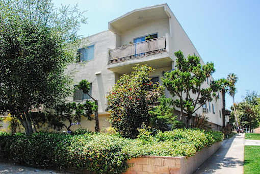A white two-story building with a balcony on the second floor.
