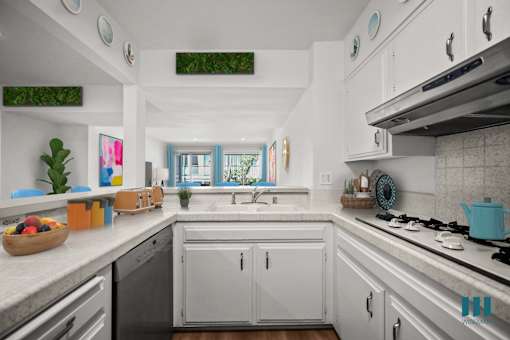 A kitchen with white cabinets and a black dishwasher.