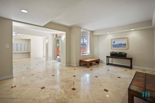 A spacious living room with tiled flooring and a wooden bench.
