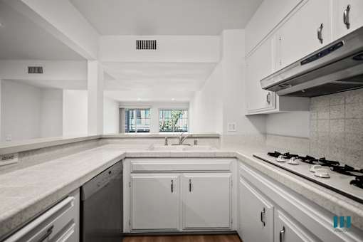 A modern kitchen with white cabinets and a black dishwasher.