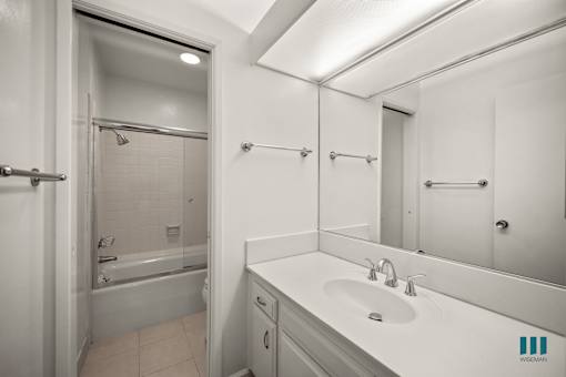 A white bathroom with a sink, mirror, and bathtub.