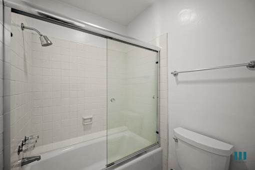 A white bathroom with a glass shower door and a white tub.