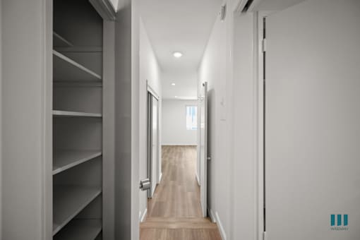 A hallway with a wooden floor and white walls.