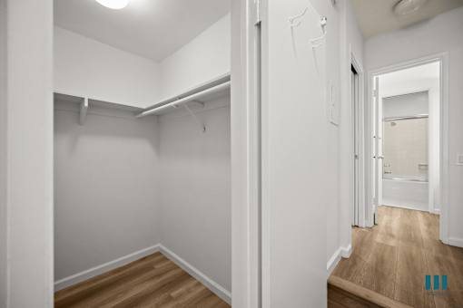 A white room with a wooden floor and a doorway leading to another room.