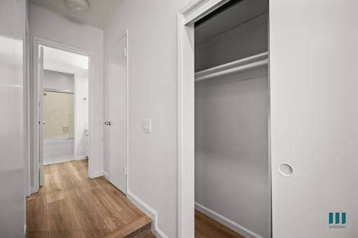 A white hallway with a wooden floor and a white door.