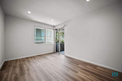 A room with wooden flooring and a window with blinds.