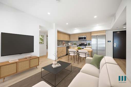 A modern living room with a white sofa, a black coffee table, and a television on the wall.