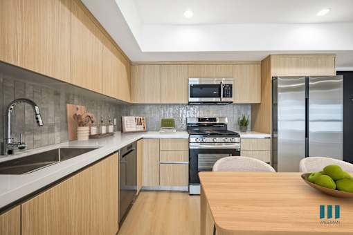 A modern kitchen with wooden cabinets and a stainless steel refrigerator.