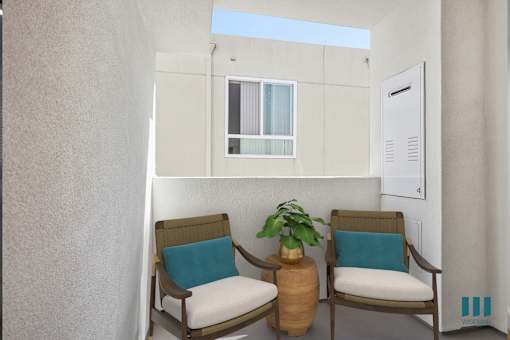 Two chairs with blue pillows sit in front of a white wall.