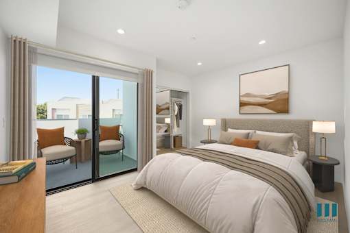 A bedroom with a large bed and a view of the outside through the sliding glass doors.