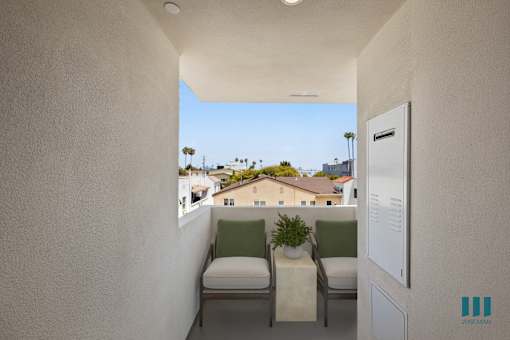 A balcony with two chairs and a table with a plant on it.