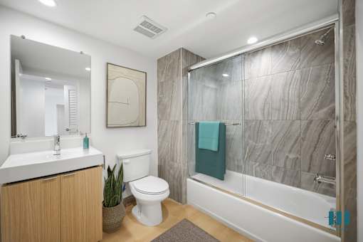 A bathroom with a white toilet, a white sink, and a glass shower stall.