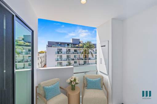 A living room with a large screen on the wall showing a building and a balcony.
