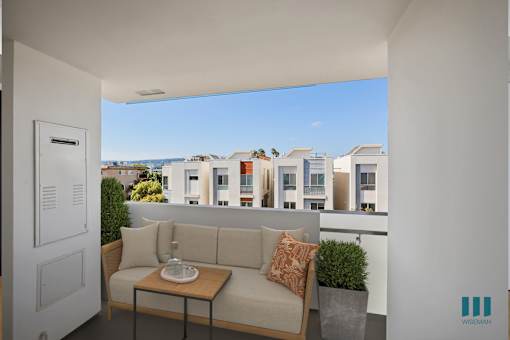 A balcony with a sofa and a table with a vase on it.