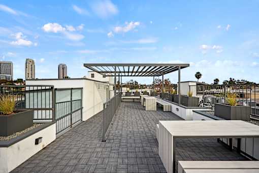 A rooftop patio with a long table and chairs under a canopy.