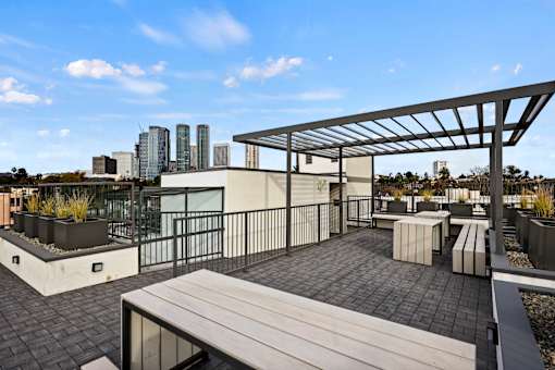 A rooftop patio with a bench and a metal pergola.