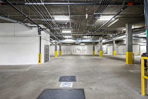A large, empty parking garage with concrete floors and yellow bollards.