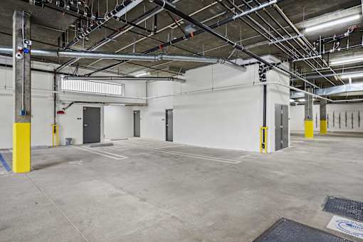 A large, empty parking garage with a concrete floor and yellow bollards.