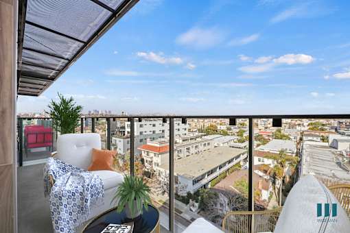 A balcony with a couch and a plant on it overlooks a cityscape.