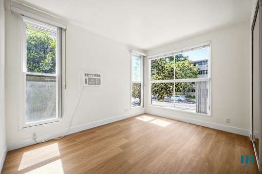Bedroom with Multiple Windows, Vinyl Flooring, and a Mirrored Closet
