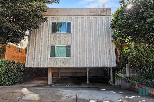 A concrete building with a striped facade and a window with a green curtain.
