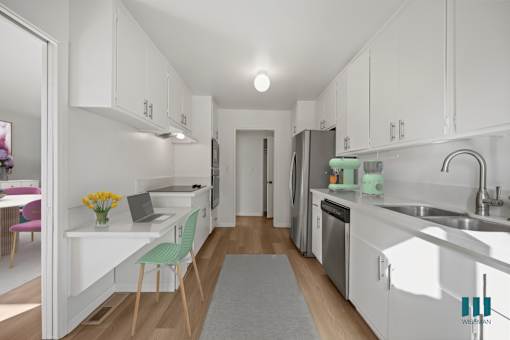 A kitchen with white cabinets and a grey rug on the floor.