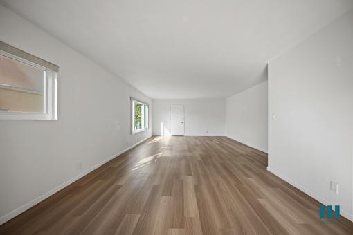 A room with wooden flooring and white walls.
