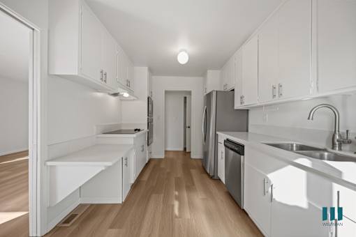 A kitchen with white cabinets and wooden floors.
