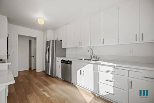 A kitchen with white cabinets and a wooden floor.