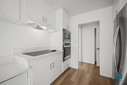 A modern kitchen with white cabinets and stainless steel appliances.