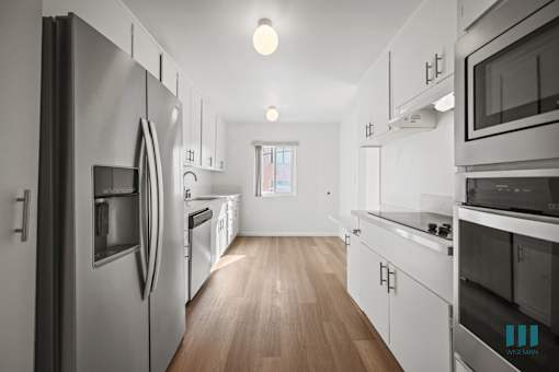 A modern kitchen with stainless steel appliances and wooden floors.