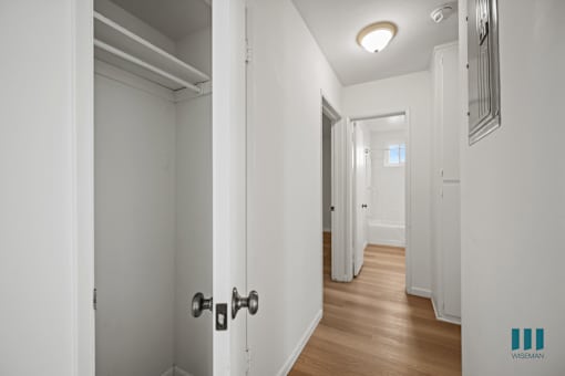 A hallway with white walls and wood floors.