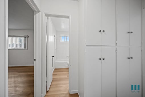 A hallway with white doors and cabinets.