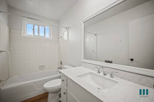 A white bathroom with a tub, toilet, sink, and mirror.