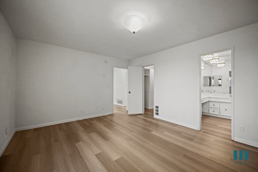 A large empty room with wooden floors and white walls.