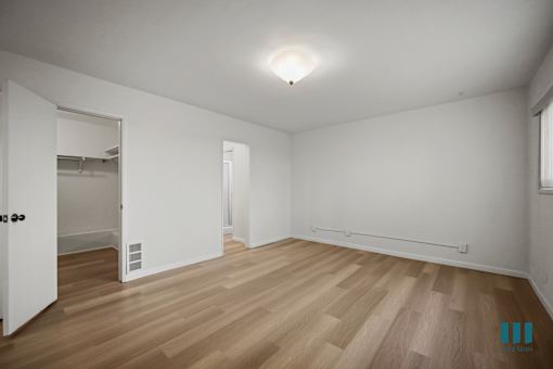A room with wooden flooring and white walls.